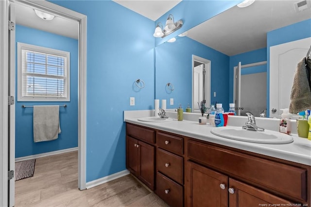 full bath featuring double vanity, a sink, visible vents, and baseboards