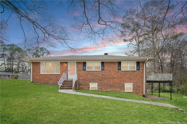 view of front of home with brick siding, a deck, and a yard