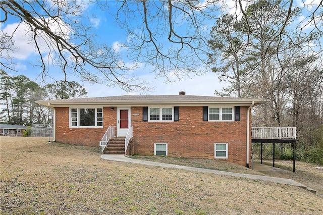 view of front facade featuring entry steps, a front yard, a deck, and brick siding