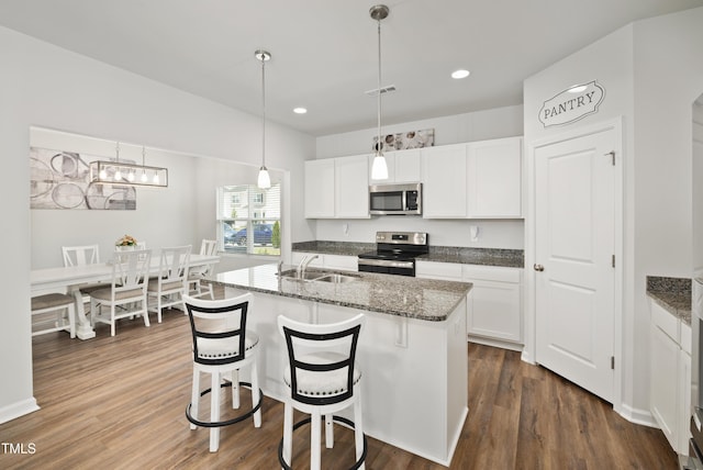 kitchen with appliances with stainless steel finishes, dark wood-style flooring, visible vents, and a sink