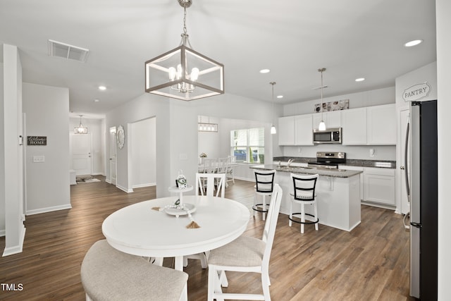 dining space with an inviting chandelier, visible vents, and wood finished floors