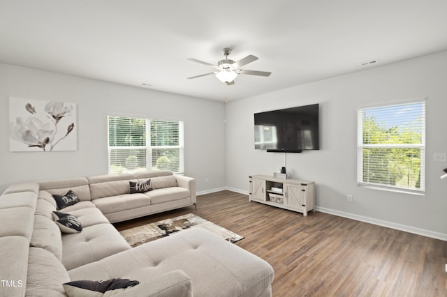 living area featuring a wealth of natural light, a ceiling fan, baseboards, and wood finished floors