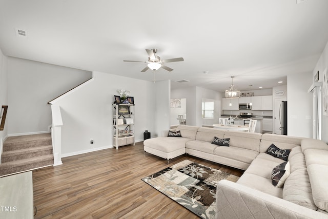 living room featuring visible vents, baseboards, a ceiling fan, stairway, and light wood-type flooring