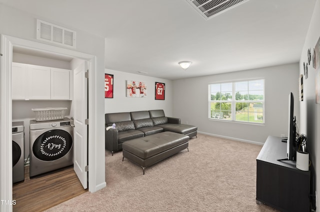 living room featuring baseboards, washing machine and dryer, visible vents, and light colored carpet