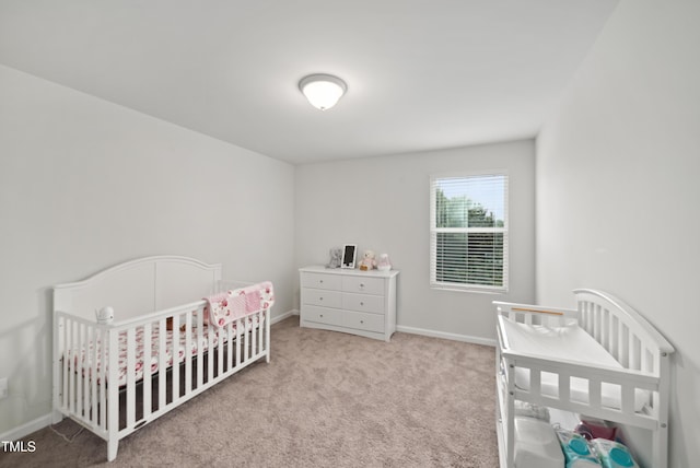 carpeted bedroom with a nursery area and baseboards