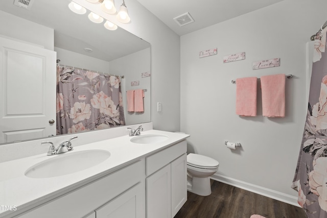 bathroom with visible vents, a sink, toilet, and wood finished floors