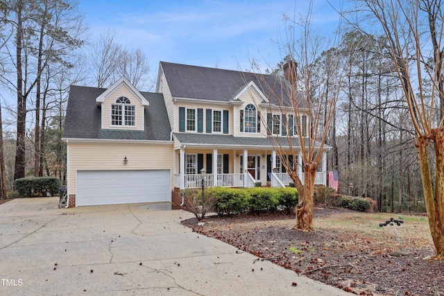 colonial-style house featuring a porch, an attached garage, driveway, and roof with shingles