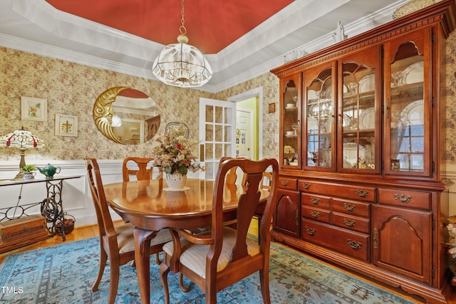 dining area featuring a tray ceiling, wood finished floors, wainscoting, wallpapered walls, and a chandelier