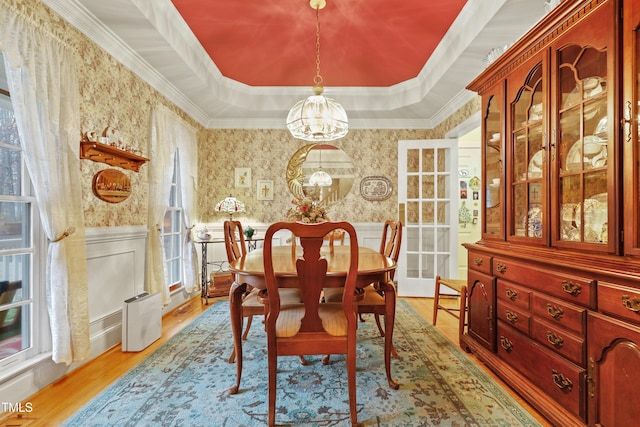 dining area with a wainscoted wall, a raised ceiling, and wallpapered walls