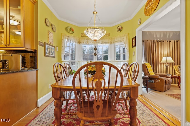 dining space with baseboards, wood finished floors, and ornamental molding