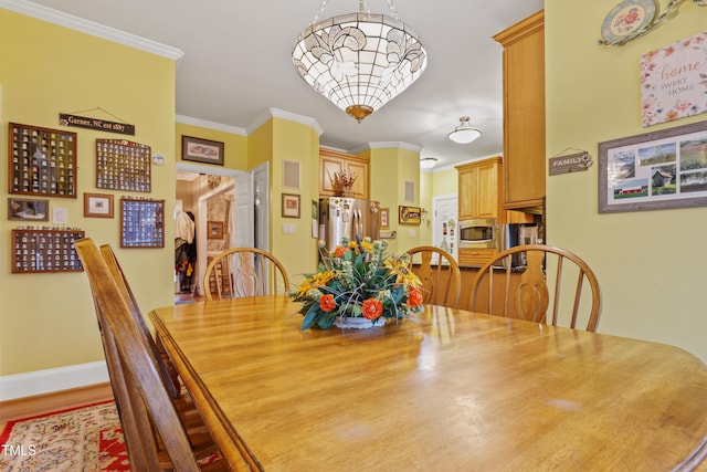 dining space with baseboards, wood finished floors, and ornamental molding