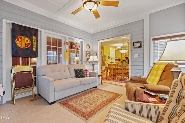 living room with carpet, a ceiling fan, and ornamental molding