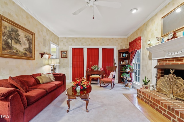 living area with a brick fireplace, wallpapered walls, carpet, ornamental molding, and a ceiling fan