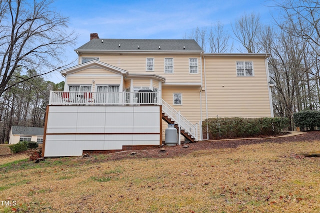 back of property featuring stairs, a deck, a yard, and a chimney