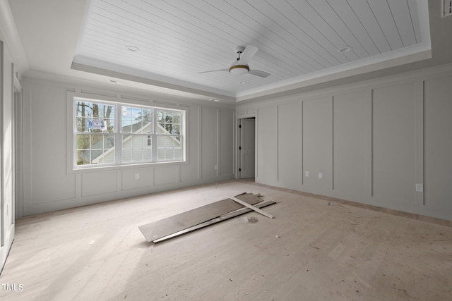 unfurnished room featuring ornamental molding, a tray ceiling, wooden ceiling, a decorative wall, and ceiling fan