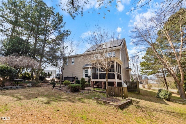 rear view of property featuring a sunroom, stairs, and a lawn