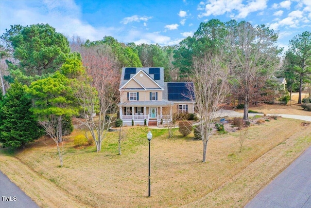 view of front of property featuring solar panels, a porch, and a front yard