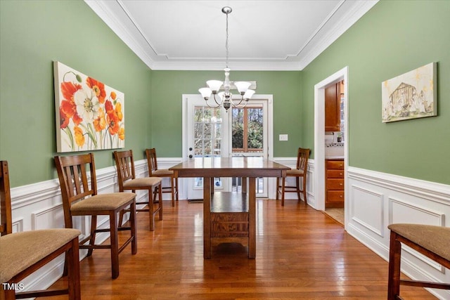 dining room with a chandelier, a wainscoted wall, crown molding, and hardwood / wood-style flooring