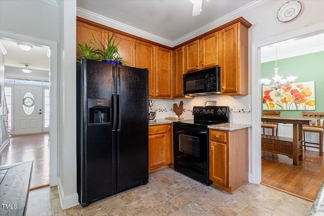 kitchen featuring black appliances, a chandelier, brown cabinetry, and crown molding