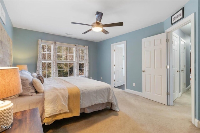 bedroom with a ceiling fan, light carpet, baseboards, and ensuite bathroom