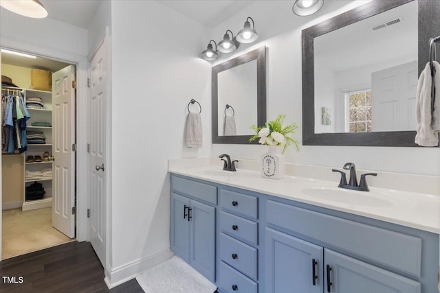 bathroom featuring wood finished floors, visible vents, a sink, and double vanity