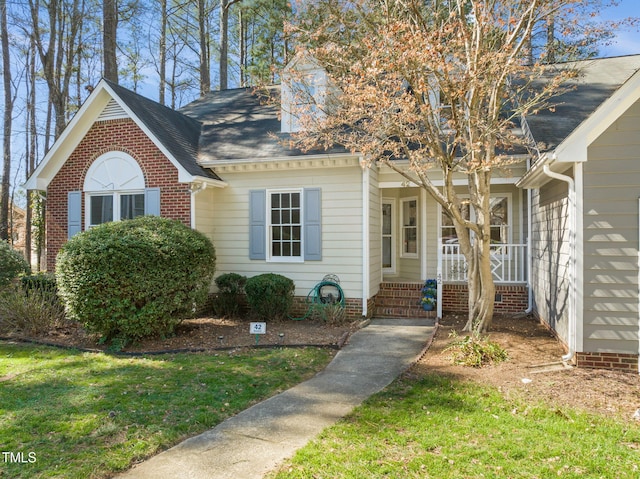 view of front of home with roof with shingles, a porch, and a front yard