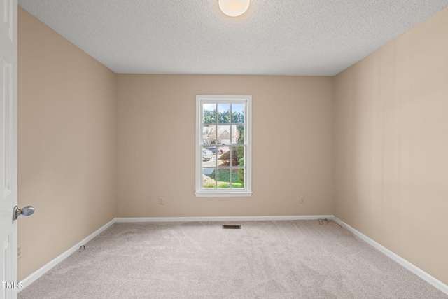 carpeted empty room with visible vents, baseboards, and a textured ceiling