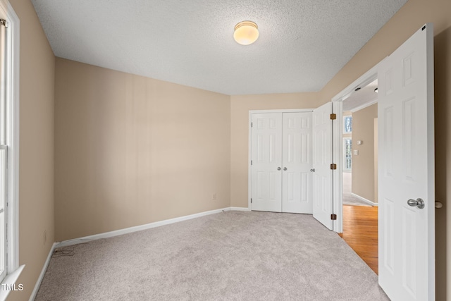 unfurnished bedroom with a closet, a textured ceiling, baseboards, and carpet floors