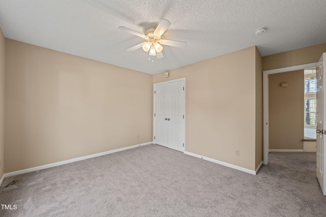 unfurnished bedroom featuring baseboards, carpet, ceiling fan, and a textured ceiling