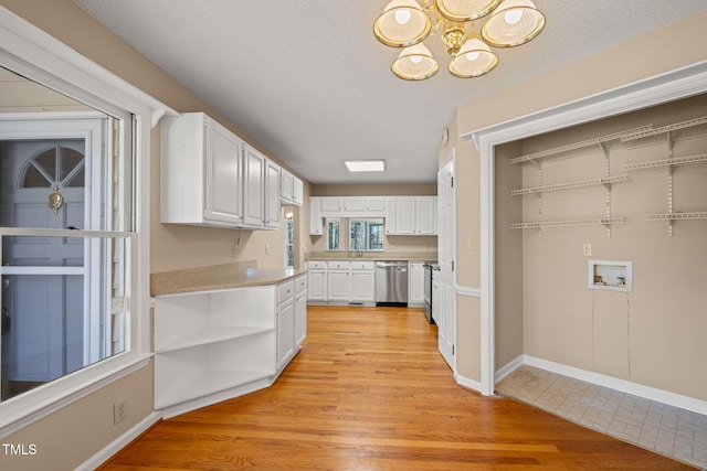 kitchen featuring light wood finished floors, dishwasher, light countertops, white cabinets, and open shelves