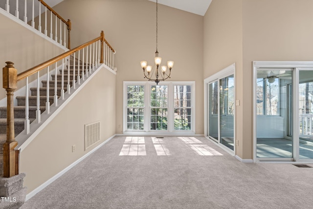 unfurnished dining area featuring a chandelier, visible vents, a high ceiling, and carpet