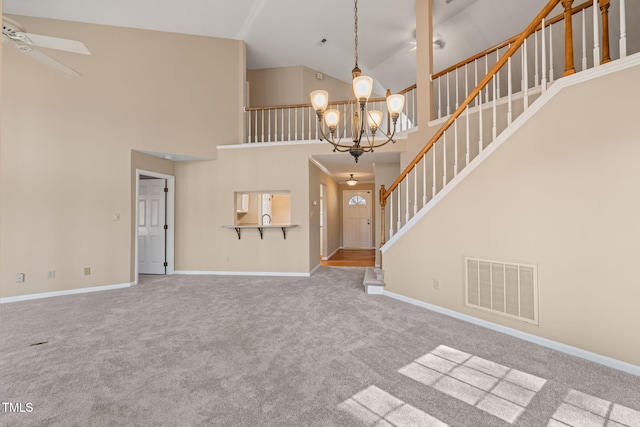 unfurnished living room featuring visible vents, baseboards, stairs, carpet floors, and ceiling fan with notable chandelier