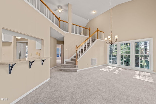 unfurnished living room with visible vents, baseboards, stairway, carpet flooring, and high vaulted ceiling