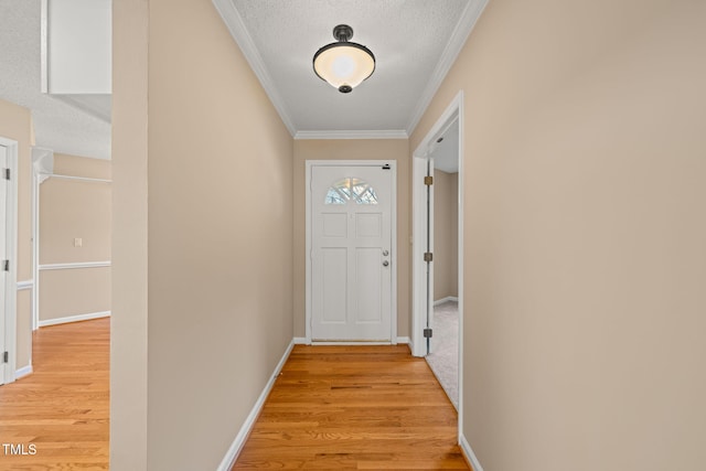 doorway to outside featuring baseboards, a textured ceiling, crown molding, and light wood-style floors