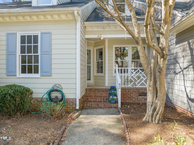 doorway to property with covered porch and roof with shingles