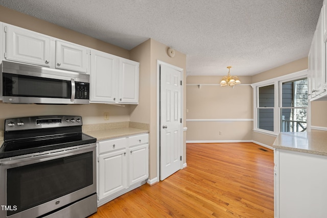 kitchen with light wood-type flooring, light countertops, appliances with stainless steel finishes, a textured ceiling, and white cabinetry