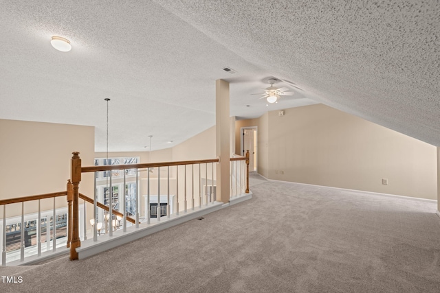 hall with vaulted ceiling, carpet flooring, visible vents, and a textured ceiling