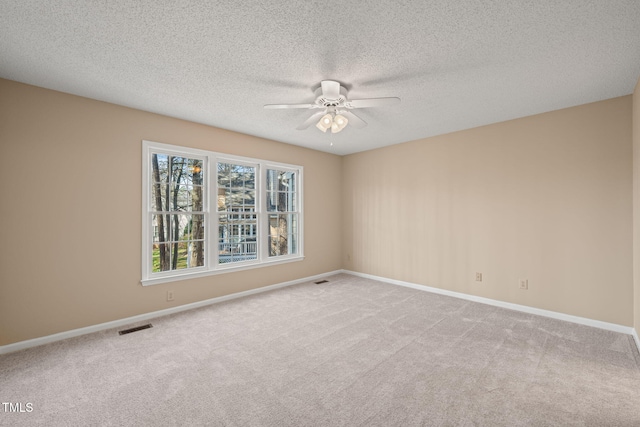 empty room with visible vents, ceiling fan, baseboards, light carpet, and a textured ceiling