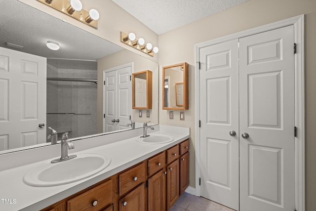 full bath featuring tile patterned floors, double vanity, a textured ceiling, and a sink