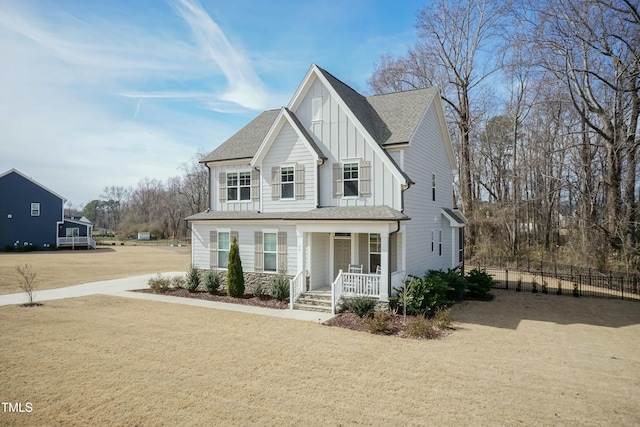 view of front of property featuring fence, a porch, board and batten siding, and roof with shingles