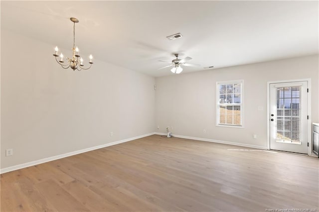 spare room featuring baseboards, ceiling fan with notable chandelier, visible vents, and light wood-style floors