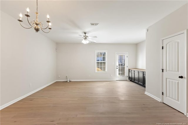 spare room with ceiling fan with notable chandelier, light wood-type flooring, visible vents, and baseboards