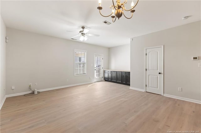 unfurnished room featuring ceiling fan with notable chandelier, light wood-style flooring, visible vents, and baseboards