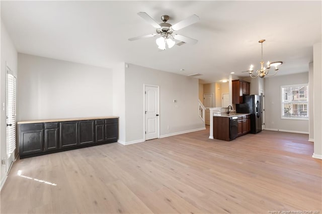 kitchen with open floor plan, black appliances, a sink, and light countertops