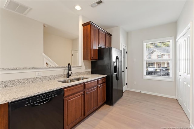 kitchen with light stone counters, visible vents, a sink, and black appliances