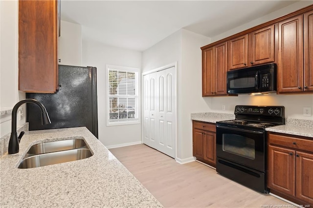 kitchen featuring black appliances, brown cabinets, a sink, and light wood finished floors