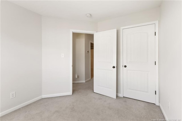 unfurnished bedroom featuring baseboards, a closet, and light colored carpet