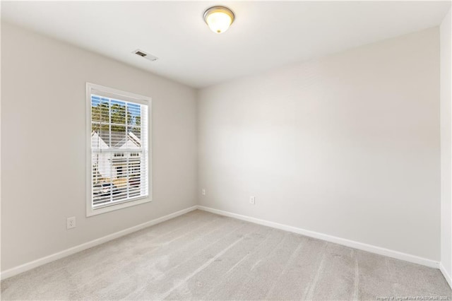 carpeted spare room with visible vents and baseboards