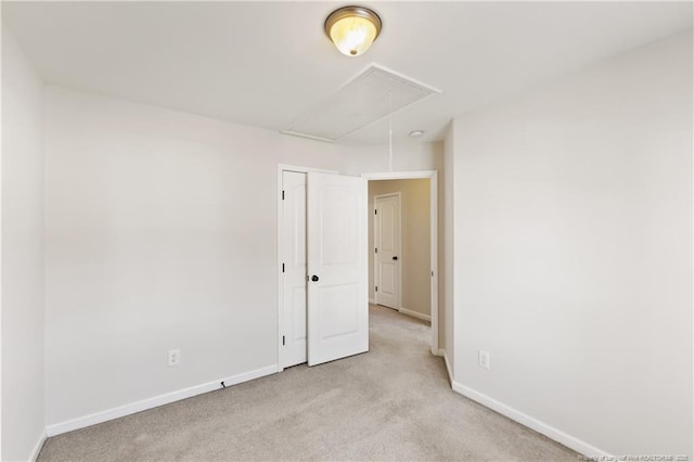 unfurnished room featuring attic access, light carpet, and baseboards