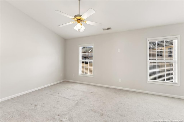 carpeted empty room with visible vents, lofted ceiling, a ceiling fan, and baseboards